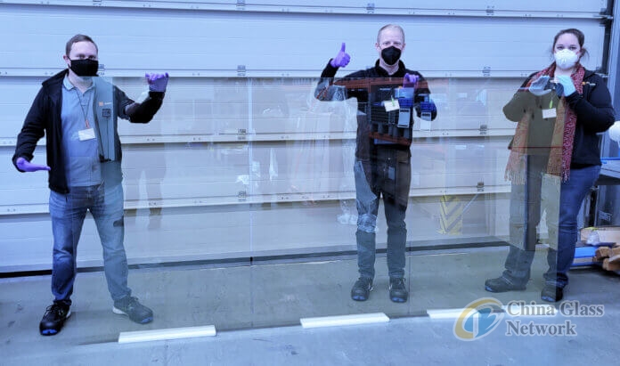 Image-of-Ubiquitous-Energy-team-holding-1.5-x-3.0-meter-size-glass-coated-with-one-of-Ubiquitous-Energys-UE-Power-transparent-solar-materials-696x411.jpg
